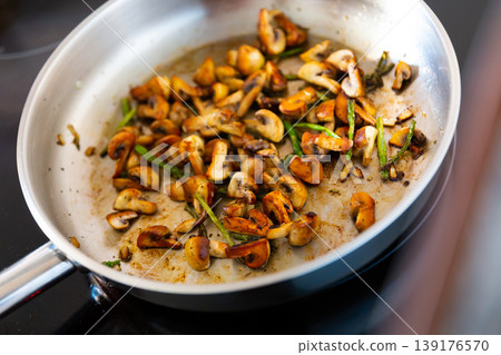 Finely chopped champignons and young asparagus shoots are fried in frying pan. Finely chopped champignons and young asparagus shoots are fried in frying pan. 139176570