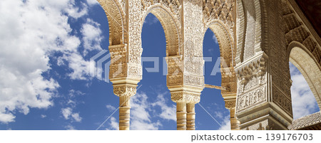 Arches in Islamic (Moorish) style (against the background of a beautiful sky with clouds) in Alhambra, Granada, Spain Arches in Islamic (Moorish) style (against the background of a beautiful sky with clouds) in Alhambra, Granada, Spain 139176703