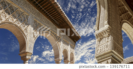 Arches in Islamic (Moorish) style (against the background of a beautiful sky with clouds) in Alhambra, Granada, Spain Arches in Islamic (Moorish) style (against the background of a beautiful sky with clouds) in Alhambra, Granada, Spain 139176711