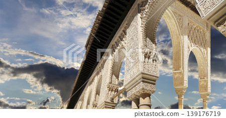 Arches in Islamic (Moorish) style (against the background of a beautiful sky with clouds) in Alhambra, Granada, Spain Arches in Islamic (Moorish) style (against the background of a beautiful sky with clouds) in Alhambra, Granada, Spain 139176719
