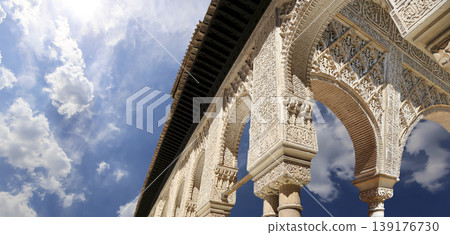 Arches in Islamic (Moorish) style (against the background of a beautiful sky with clouds) in Alhambra, Granada, Spain Arches in Islamic (Moorish) style (against the background of a beautiful sky with clouds) in Alhambra, Granada, Spain 139176730