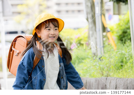 Elementary school students walking to school with their backpacks on, smiling and looking at the camera in a traffic safety image for their commute. Elementary school students walking to school with their backpacks on, smiling and looking at the camera in a traffic safety image for their commute. 139177144