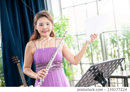 Flute classical instrument profestional player playing song. A young and elegant Asian woman plays the flute. Flute classical instrument profestional player playing song. A young and elegant Asian woman plays the flute. 139177224