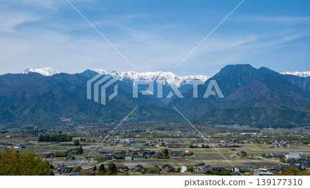 The snow-capped Northern Alps viewed from a park surrounded by fresh greenery, Azumino City, Nagano Prefecture. 139177310