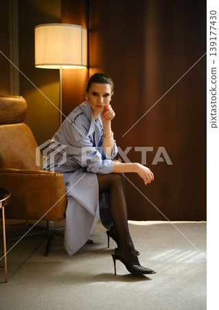 Woman sitting in a stylish chair wearing high heels in a modern interior space Woman sitting in a stylish chair wearing high heels in a modern interior space 139177430