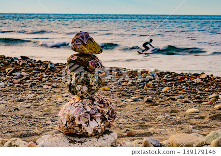 A stone wall on the beach watches over the surfers; a peaceful moment. A stone wall on the beach watches over the surfers; a peaceful moment. 139179146