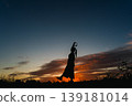 夕陽西下，一位女子在音樂中尋求慰藉，她的身影在空中勾勒出剪影。 139181014