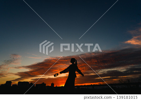 A silhouette of a woman expressing joy against the backdrop of a twilight sky. 139181015