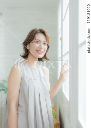 Middle-aged woman by the window Middle-aged woman by the window 139181020
