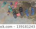 Many Pairs of Colorful Sandals and Flip Flops on Stone Floor 139181243