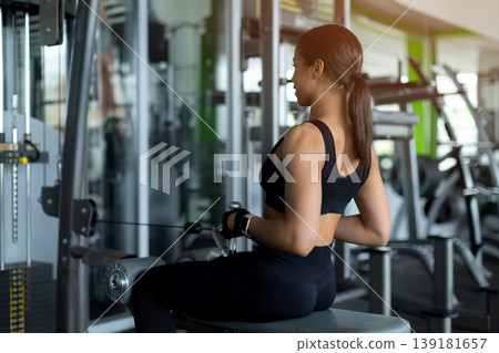 Young Black woman doing seated cable row exercise viewed from behind Young Black woman doing seated cable row exercise viewed from behind 139181657