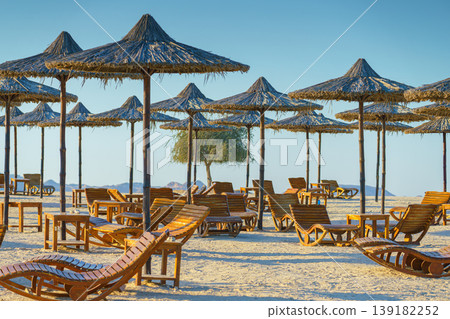 Sir Bani Yas island, United Arab Emirates, View of the beach with sun loungers and straw umbrellas, without people, at daytime Sir Bani Yas island, United Arab Emirates, View of the beach with sun loungers and straw umbrellas, without people, at daytime 139182252