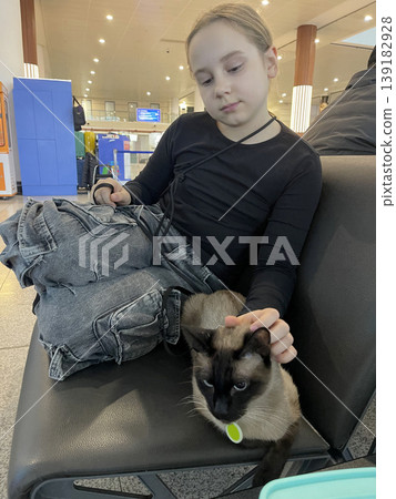 Attractive Child Girl with Cat sitting in Airport Travel Terminal. Pet Travel Attractive Child Girl with Cat sitting in Airport Travel Terminal. Pet Travel 139182928