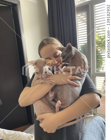 Beautiful child with cat pet indoors. Girl 10 years old and hairless kitten 139182932