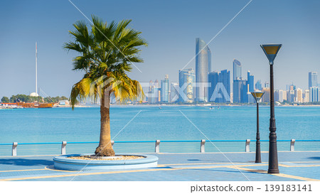 Abu Dhabi, United Arab Emirates - Jan 10 2024, Panoramic view of the embankment with a palm tree and a lantern, downtown skyscrapers are visible in the background, Abu Dhabi, United Arab Emirates  139183141