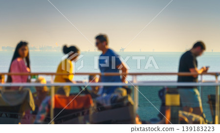 Manama, Bahrain- Jan 09 2024, Panoramic view of people walking on the upper deck of the MSC Virtuosa cruise ship, in the background the sea with oil rigs, at sunset Manama, Bahrain Manama, Bahrain- Jan 09 2024, Panoramic view of people walking on the upper deck of the MSC Virtuosa cruise ship, in the background the sea with oil rigs, at sunset Manama, Bahrain 139183223