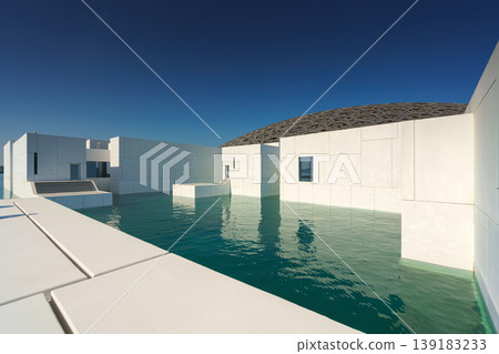 Abu Dhabi, United Arab Emirates - Jan 10 2024, Panoramic view of the snow-white facade of the Louvre Abu Dhabi with a metal dome surrounded by water, at daytime, Abu Dhabi, United Arab Emirates Abu Dhabi, United Arab Emirates - Jan 10 2024, Panoramic view of the snow-white facade of the Louvre Abu Dhabi with a metal dome surrounded by water, at daytime, Abu Dhabi, United Arab Emirates 139183233