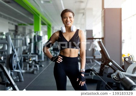 Confident Black woman in black sports bra and leggings posing in gym Confident Black woman in black sports bra and leggings posing in gym 139183329