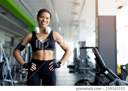Confident smiling young Black woman standing in gym with hands on hips Confident smiling young Black woman standing in gym with hands on hips 139183331