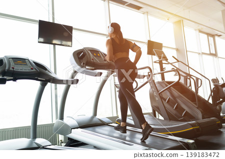 Young Black woman running on treadmill in gym viewed from behind 139183472