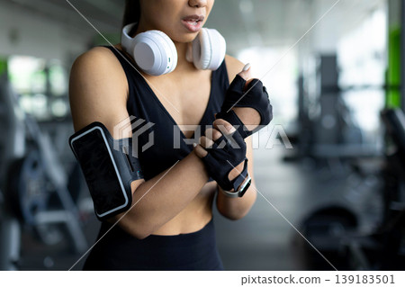 Young Black woman in gym suffering wrist pain, grimacing while holding arm Young Black woman in gym suffering wrist pain, grimacing while holding arm 139183501