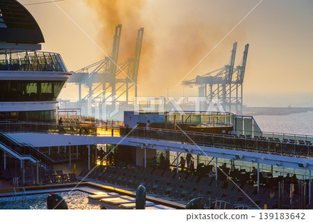 Manama, Bahrain - Jan 08 2024, Panoramic view of Bahrain commercial port with blue cranes, with upper deck of MSC Virtuosa cruise ship on foreground, by the morning, dawn, sunrise, Manama, Bahrain 139183642