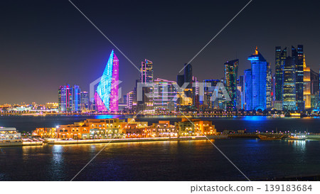 Doha, Qatar - Jan 07 2024, a panoramic view of Doha, Mina district Doha port in the foreground, skyscrapers and Al Mana tower in the background, with illumination, at nighttime, Doha, Qatar Doha, Qatar - Jan 07 2024, a panoramic view of Doha, Mina district Doha port in the foreground, skyscrapers and Al Mana tower in the background, with illumination, at nighttime, Doha, Qatar 139183684