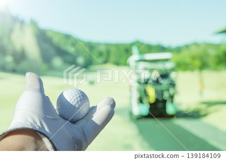 他用戴著手套的手舉起高爾夫球。 他用戴著手套的手舉起高爾夫球。 139184109