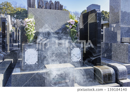 The smoke from incense burning in front of the grave and the tombstone The smoke from incense burning in front of the grave and the tombstone 139184140