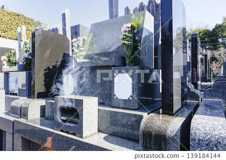 The smoke from incense burning in front of the grave and the tombstone The smoke from incense burning in front of the grave and the tombstone 139184144