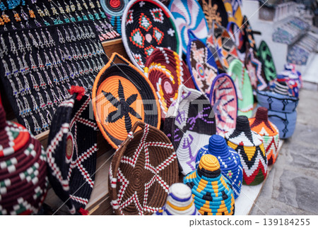 Colorful handcrafted baskets and woven items displayed on a market stall, showcasing intricate patterns and vibrant designs in a cultural setting Colorful handcrafted baskets and woven items displayed on a market stall, showcasing intricate patterns and vibrant designs in a cultural setting 139184255