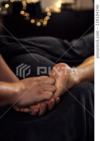 Close-up of a skilled massage therapist's hands gently massaging a client's foot, surrounded by soft lighting and cozy ambiance, promoting relaxation and wellness Close-up of a skilled massage therapist's hands gently massaging a client's foot, surrounded by soft lighting and cozy ambiance, promoting relaxation and wellness 139184340