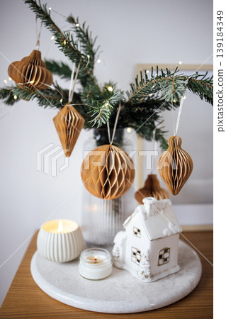 Decorative arrangement featuring honeycomb ornaments, evergreen branches, and candles on a marble tray, creating a cozy holiday atmosphere with festive charm Decorative arrangement featuring honeycomb ornaments, evergreen branches, and candles on a marble tray, creating a cozy holiday atmosphere with festive charm 139184349