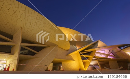 Doha, Qatar - Jan 06 2024, a bottom up view of National Museum of Qatar part of facade, exterior, in courtyard, patio shaped like a desert rose, at nighttime, with illumination, Doha, Qatar  139184666