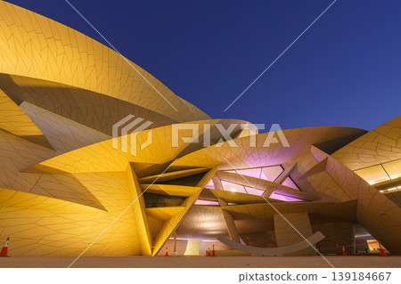 Doha, Qatar - Jan 06 2024, a bottom up view of National Museum of Qatar part of facade, exterior, in courtyard, patio shaped like a desert rose, at nighttime, with illumination, Doha, Qatar Doha, Qatar - Jan 06 2024, a bottom up view of National Museum of Qatar part of facade, exterior, in courtyard, patio shaped like a desert rose, at nighttime, with illumination, Doha, Qatar 139184667