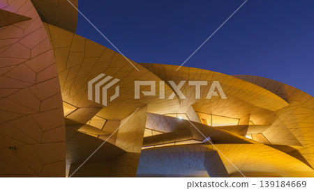 Doha, Qatar - Jan 06 2024, a bottom up view of National Museum of Qatar part of facade, exterior, in courtyard, patio shaped like a desert rose, at nighttime, with illumination, Doha, Qatar  139184669