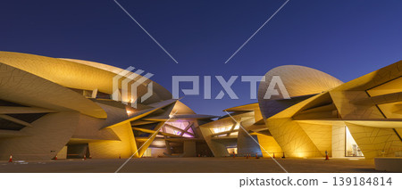 Doha, Qatar - Jan 06 2024, a bottom up view of National Museum of Qatar part of facade, exterior, in courtyard, patio shaped like a desert rose, at nighttime, with illumination, Doha, Qatar Doha, Qatar - Jan 06 2024, a bottom up view of National Museum of Qatar part of facade, exterior, in courtyard, patio shaped like a desert rose, at nighttime, with illumination, Doha, Qatar 139184814