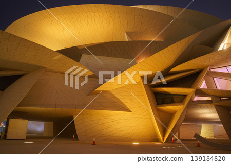 Doha, Qatar - Jan 06 2024, a bottom up view of National Museum of Qatar part of facade, exterior, in courtyard, patio shaped like a desert rose, at nighttime, with illumination, Doha, Qatar  139184820
