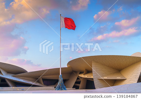 Doha, Qatar - Jan 06 2024, a view of flagpole with the flag of Qatar, fluttering in the wind, with the National Museum of Qatar on background, at evening with cloudy sky, Doha, Qatar 139184867