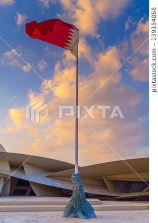 Doha, Qatar - Jan 06 2024, a view of flagpole with the flag of Qatar, fluttering in the wind, with the National Museum of Qatar on background, at evening with cloudy sky, Doha, Qatar 139184868