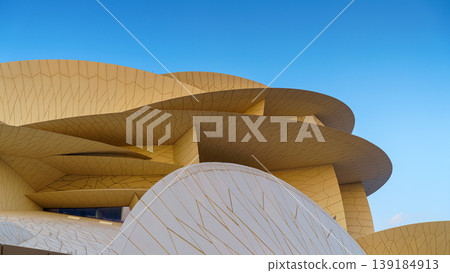Doha, Qatar - Jan 06 2024, a panoramic view of National Museum of Qatar facade, exterior, shaped like a desert rose, at evening with blue sky, Doha, Qatar  139184913
