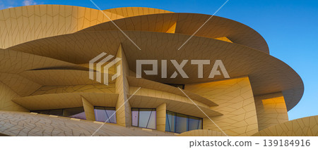 Doha, Qatar - Jan 06 2024, a panoramic view of National Museum of Qatar facade, exterior, shaped like a desert rose, at evening with blue sky, Doha, Qatar  139184916