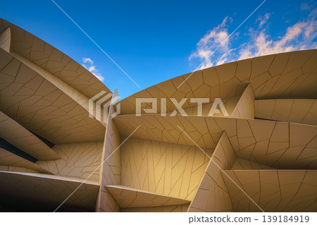 Doha, Qatar - Jan 06 2024, a panoramic view of National Museum of Qatar facade, exterior, shaped like a desert rose, at evening with blue sky, Doha, Qatar  139184919