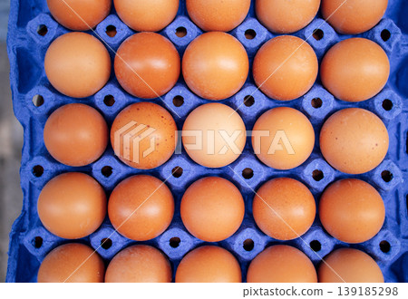Fresh brown eggs arranged neatly in a blue carton, showcasing various shades and textures, emphasizing natural food presentation and organic farming practices Fresh brown eggs arranged neatly in a blue carton, showcasing various shades and textures, emphasizing natural food presentation and organic farming practices 139185298