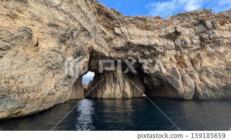 Huge rock with caves on the coast of one of the islands around Comino island Huge rock with caves on the coast of one of the islands around Comino island 139185659