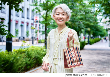 一位微笑的健壯老年女性漫步在城市中的肖像。 139186055