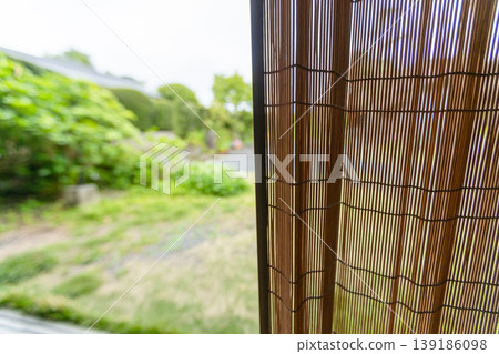 透過竹簾欣賞日式花園中令人神清氣爽的夏日生活,周圍環繞著鬱鬱蔥蔥的新生綠植。 透過竹簾欣賞日式花園中令人神清氣爽的夏日生活,周圍環繞著鬱鬱蔥蔥的新生綠植。 139186098