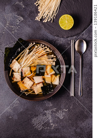 Asian-style soup with squid, tofu and enoki mushrooms. 139186421