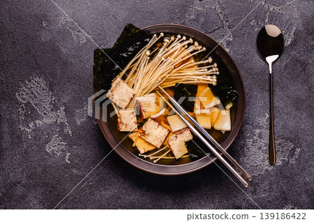 Asian-style soup with squid, tofu and enoki mushrooms. 139186422