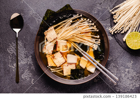 Asian-style soup with squid, tofu and enoki mushrooms. Asian-style soup with squid, tofu and enoki mushrooms. 139186423